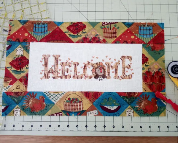 Un bordado de "Welcome" con un pavo, listo para enmarcar telas bordadas con un diseño otoñal.