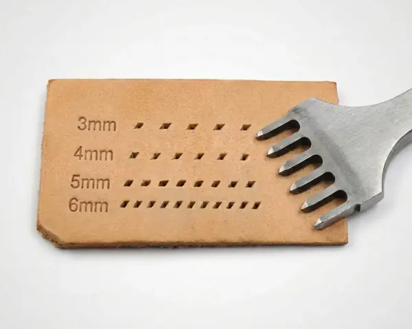 Un punzón de cuero con dientes metálicos crea filas de agujeros en una tira de cuero, mostrando diferentes tamaños de puntadas.