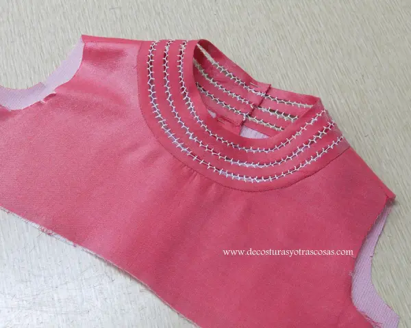 Detalle de camiseta rosa con bordado a mano en el cuello, creando un diseño delicado y único.
