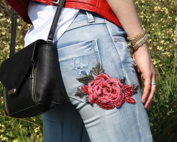 Detalle de unos pantalones vaqueros con un llamativo bordado de rosa roja, perfectos para tunear tus vaqueros y darle un toque único.