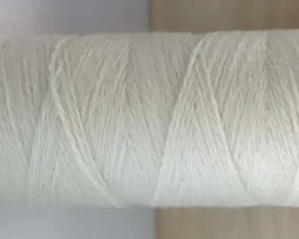 Rollo de hilo blanco de merino lana, listo para tejer prendas suaves y cálidas.