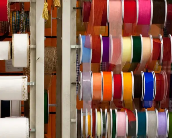 Variedad de tipos de cintas de tela en rollos, con colores y texturas diversas, ideales para manualidades y decoración.