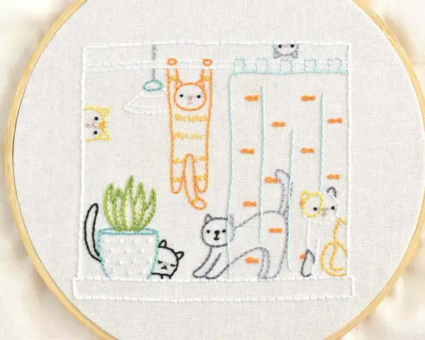 Bordado al aire con plantillas: gatos jugando en una casa de muñecas, uno colgado de una barra, otro trepando y uno más observando.