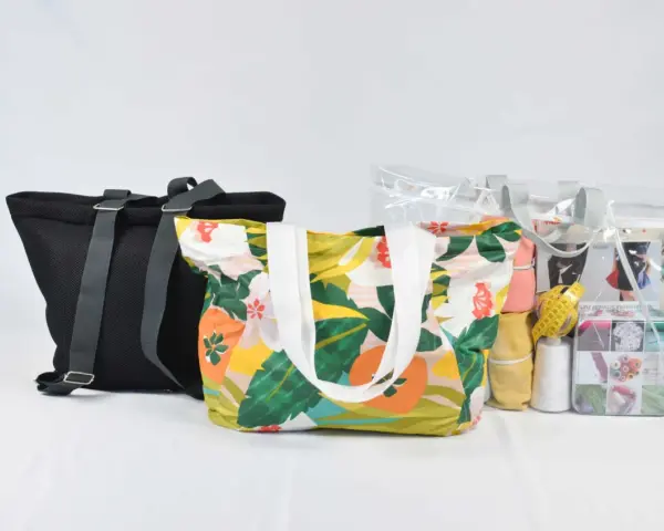 Bolsas de tela con estampado floral y una bolsa transparente con materiales de costura, incluyendo un patrón.