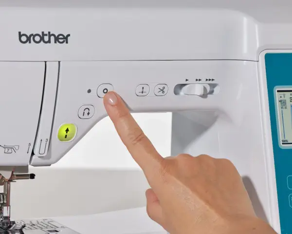 Dedo presionando botón en máquina de coser Brother. Guía para como elegir máquina de coser.
