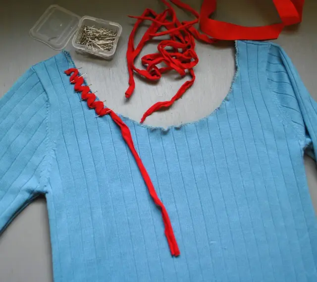 Jersey azul de punto con cuello cortado y tijeras.