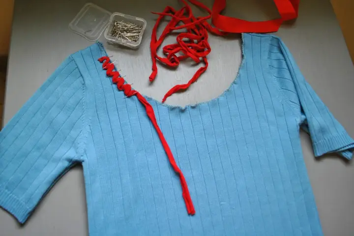 Jersey azul de punto con cuello cortado y tijeras.