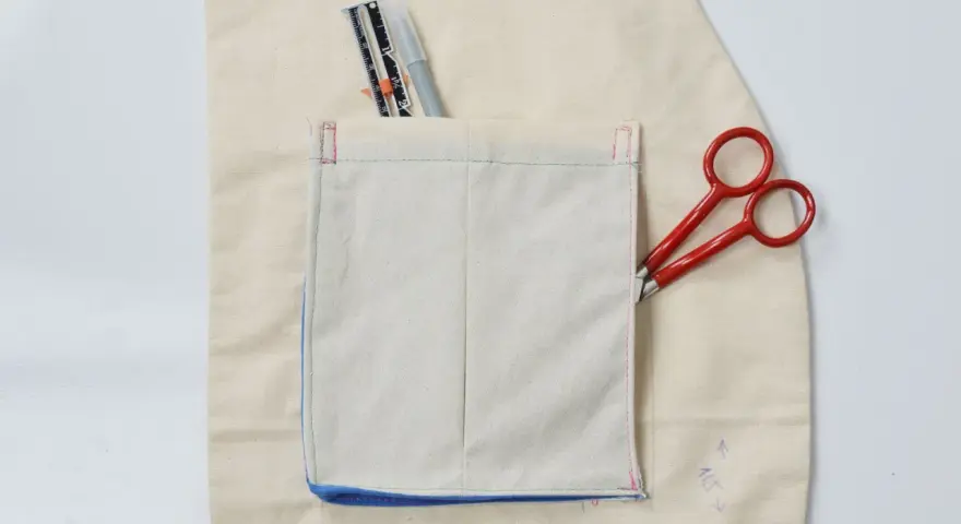 Detalles de costura y herramientas para crear diferentes tipos de bolsillos para abrigos. Tijeras rojas y un rotulador de tela.