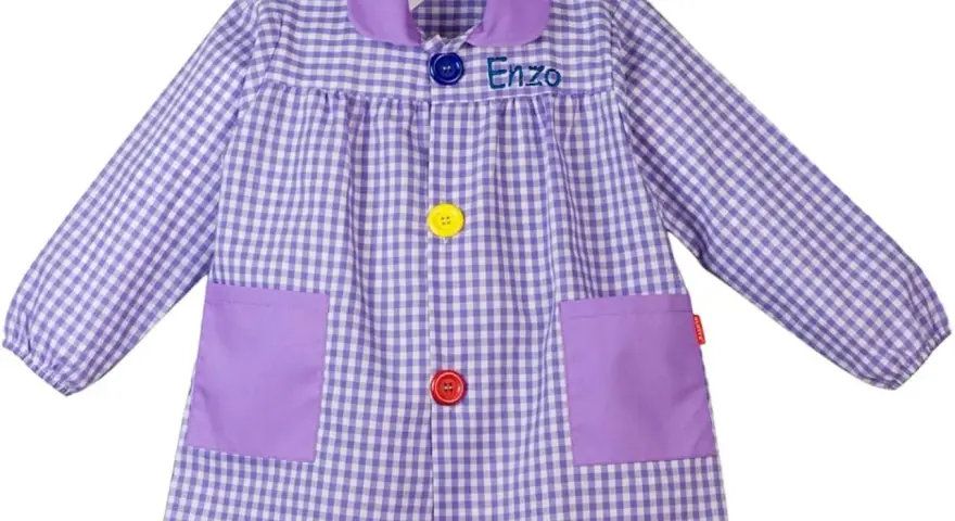 Batas con nombre bordado "Enzo", a cuadros lilas y blancos, con bolsillos y botones de colores.