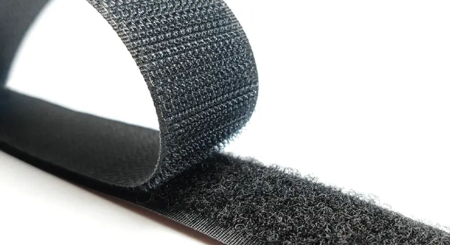Cinta negra con dos caras: una suave y otra con pequeños ganchos. Así es que es velcro, ideal para unir objetos.