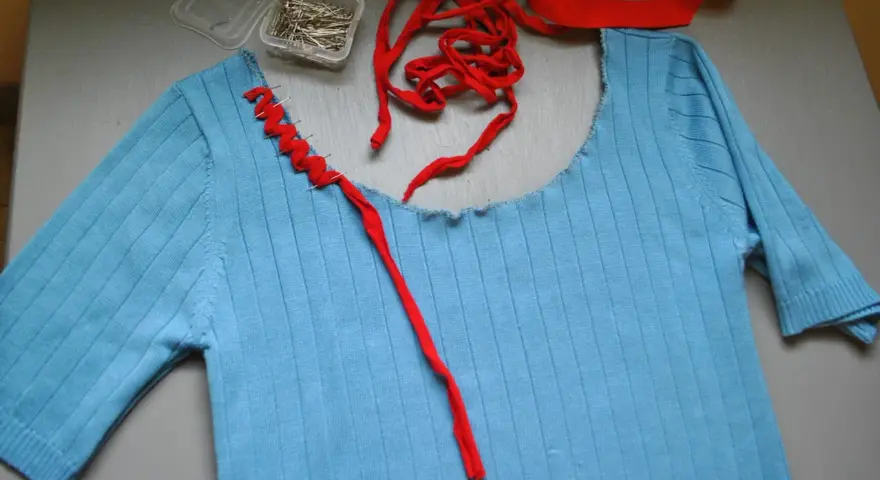 Jersey azul de punto con cuello cortado y tijeras.