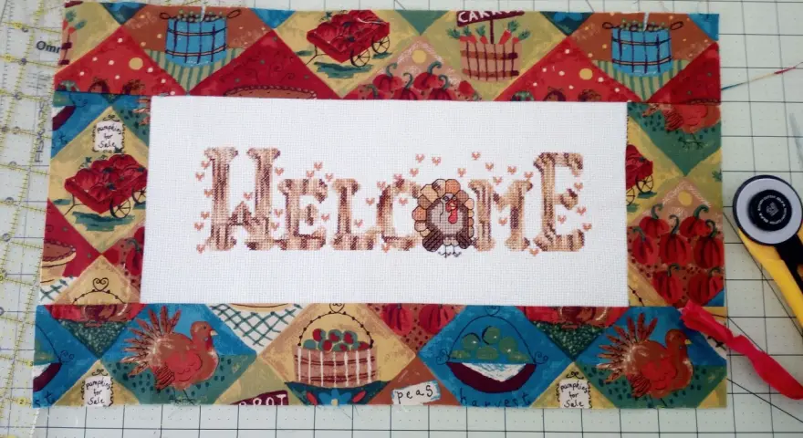 Un bordado de "Welcome" con un pavo, listo para enmarcar telas bordadas con un diseño otoñal.