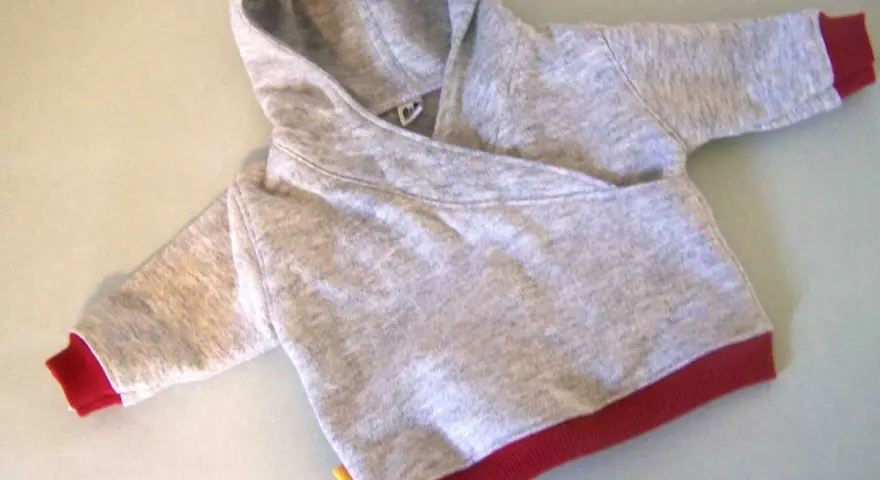 Saco de bebé gris con capucha y puños rojos. Un patrón de saco de bebé con capucha listo para coser.