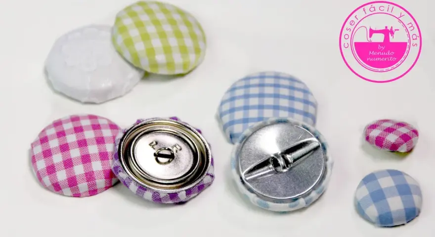 Botones forrados con tela de cuadros vichy en rosa, morado, verde y azul. Se ven los cierres metálicos.