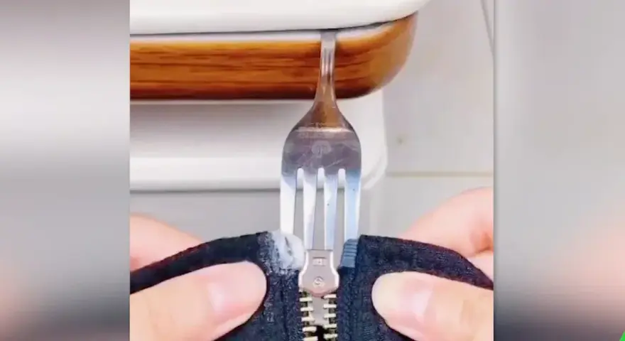 Demostración de como arreglar una cremallera con un tenedor. Un tenedor se usa para manipular una cremallera atascada.