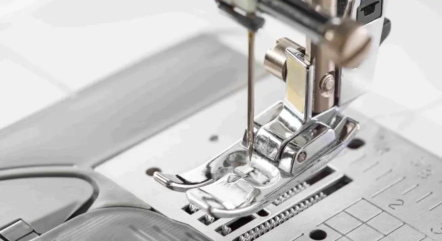 Primer plano del prensatelas de una máquina de coser, listo para guiar la tela con precisión.