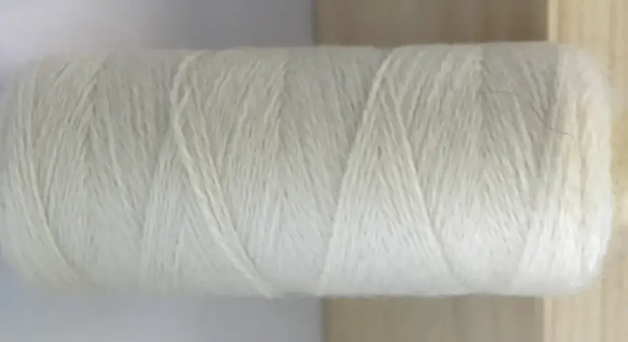 Rollo de hilo blanco de merino lana, listo para tejer prendas suaves y cálidas.