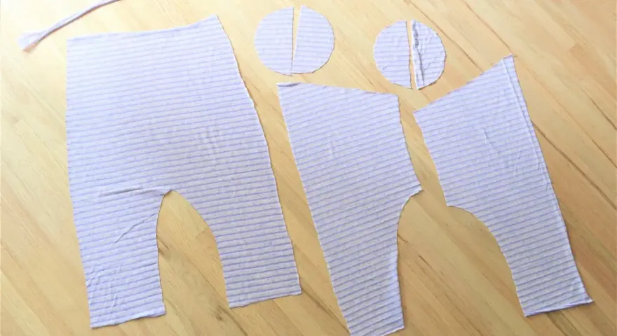 Piezas de tela a rayas lilas, listas para coser un patrón de peto para bebé.