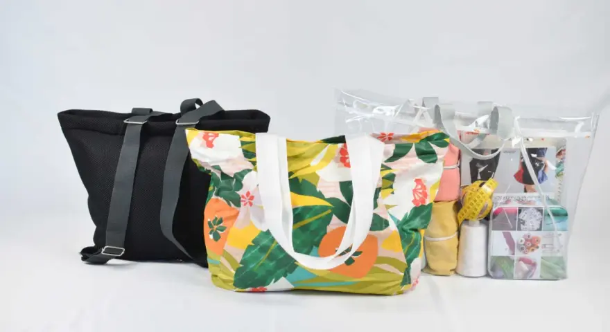 Bolsas de tela con estampado floral y una bolsa transparente con materiales de costura, incluyendo un patrón.