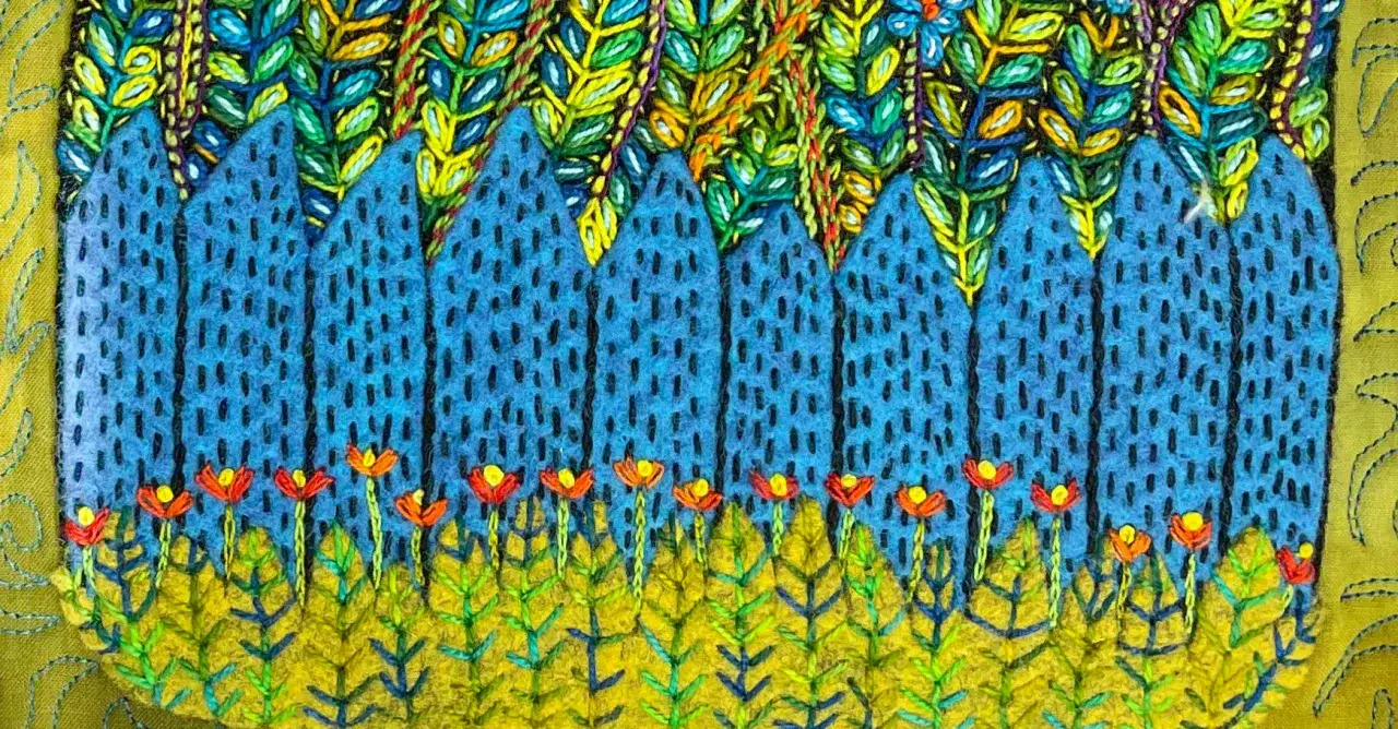 Un paisaje vibrante con un bordado creativo de montañas azules, flores rojas y follaje verde y amarillo.
