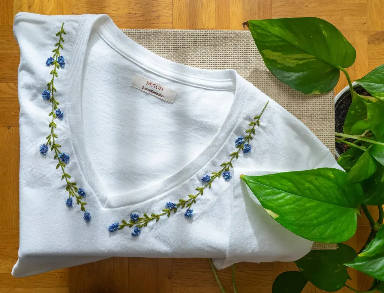 Camiseta blanca con delicado bordado floral azul a mano. Un toque de naturaleza para bordar camisetas a mano con estilo.
