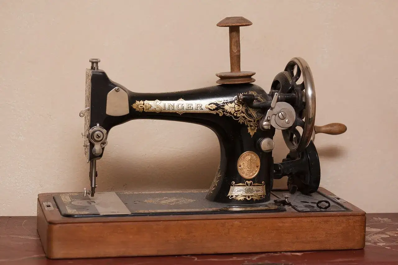 M&aacute;quina de coser Singer antigua, pieza clave en la historia de la costura, con detalles dorados y base de madera.