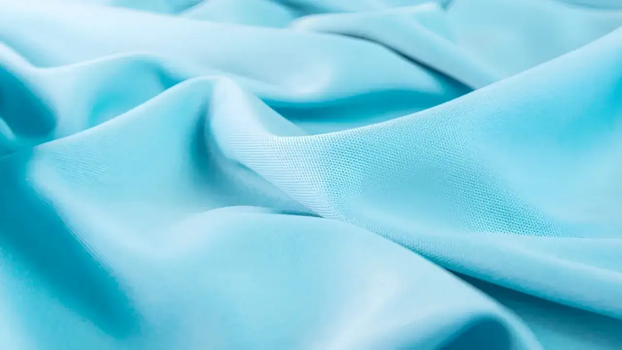 Ondas suaves de tela azul turquesa, con la textura sutil del tencel lyocell brillando bajo la luz.