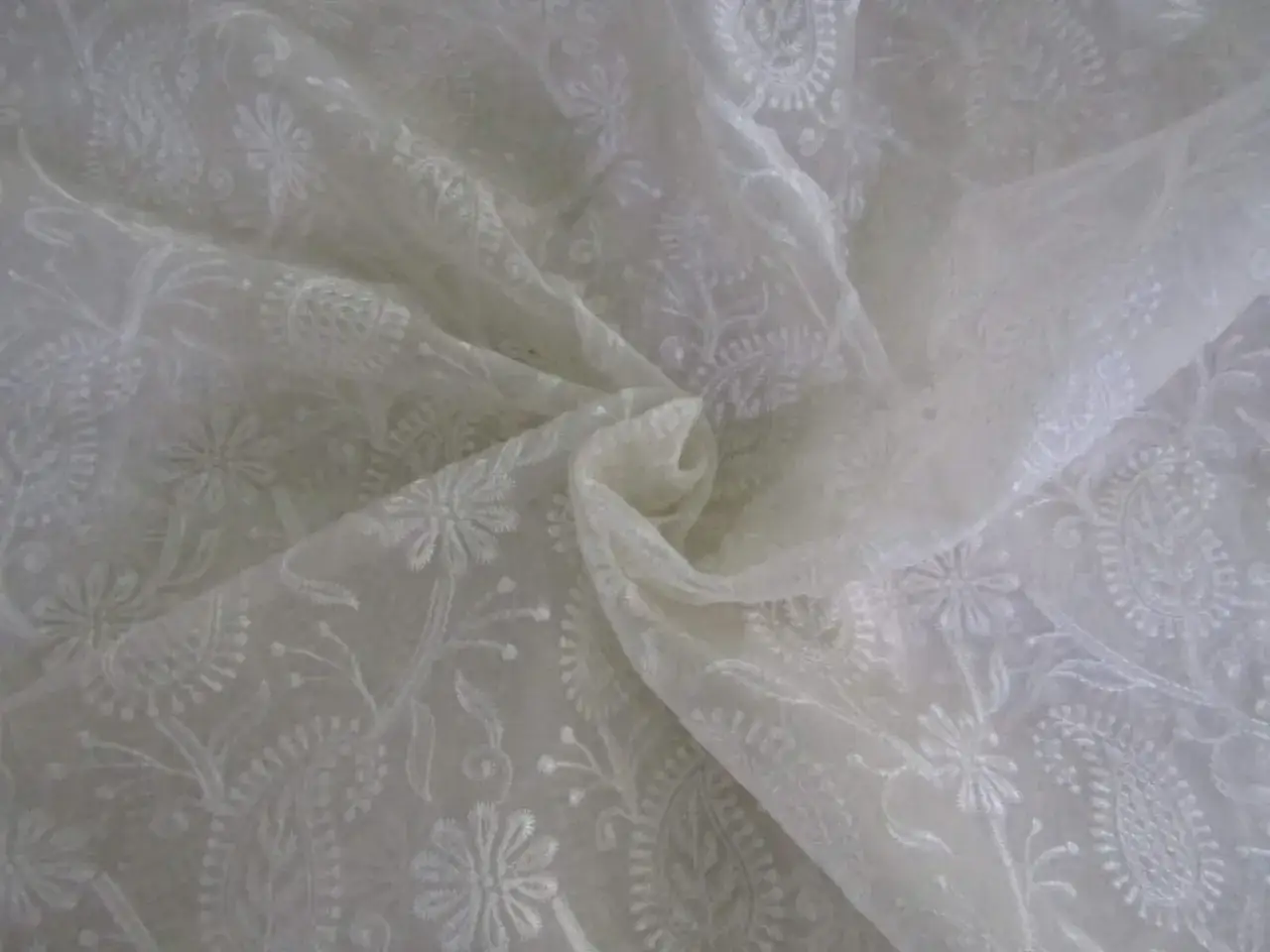 Delicado tejido blanco con bordados florales y paisley, mostrando varios tipos de organza.
