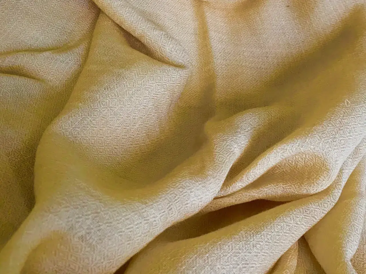Textura suave y cálida de una tela de cachemira lana, con pliegues que resaltan su delicadeza.