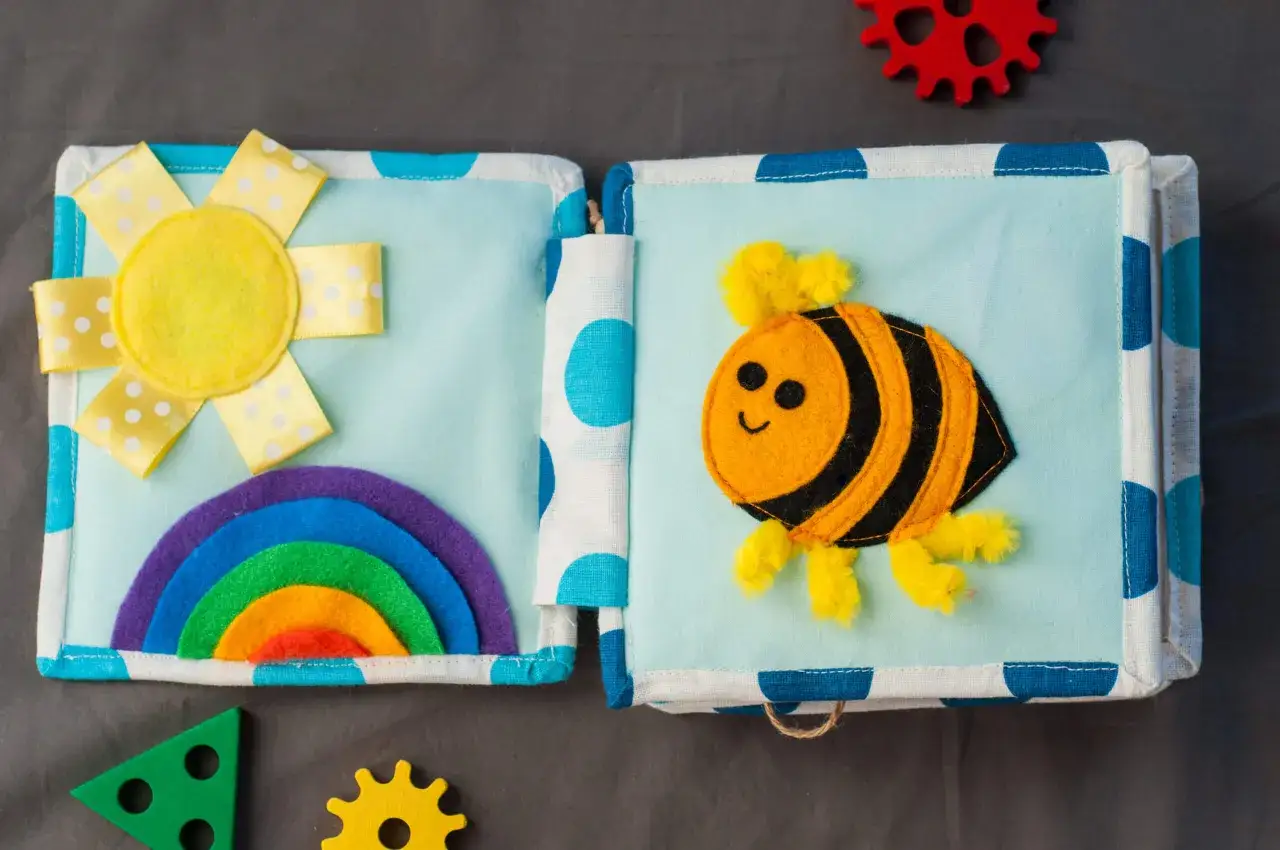 Libro de actividades de tela con un sol, arcoíris y abeja. Muchas cosas para hacer con telas y aprender.
