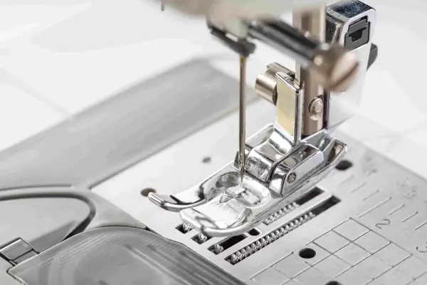 Primer plano del prensatelas de una máquina de coser, listo para guiar la tela con precisión.