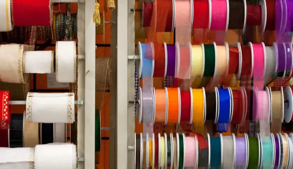 Variedad de tipos de cintas de tela en rollos, con colores y texturas diversas, ideales para manualidades y decoración.