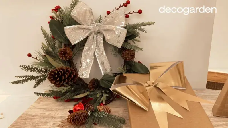 Corona navideña con lazo plateado y regalos con lazo dorado. Aprende como hacer un lazo con cinta ancha para tus decoraciones.