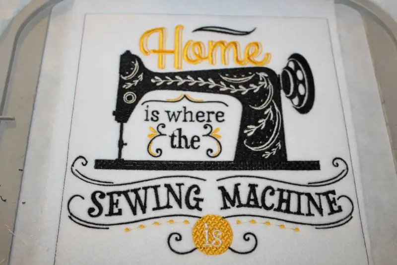 Tipografía para bordar: "Home is where the SEWING MACHINE is". Máquina de coser vintage bordada en negro y dorado.
