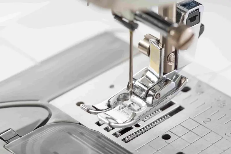 Primer plano del prensatelas de una máquina de coser, listo para guiar la tela con precisión.