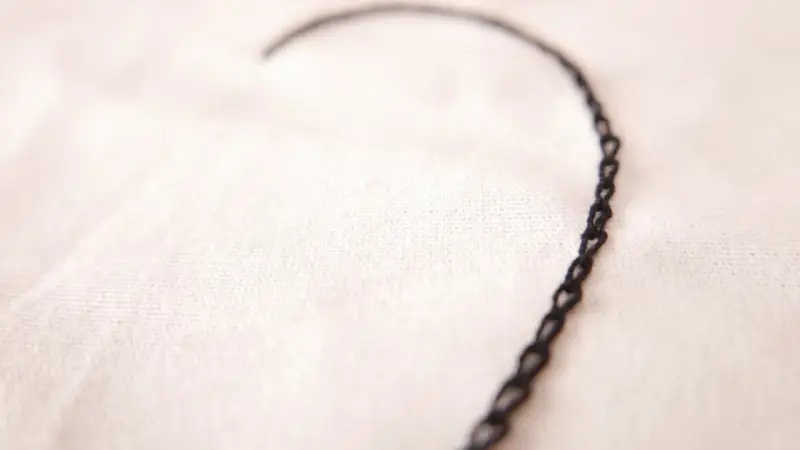 Un delicado corazón bordado con punto cadeneta sobre tela clara.